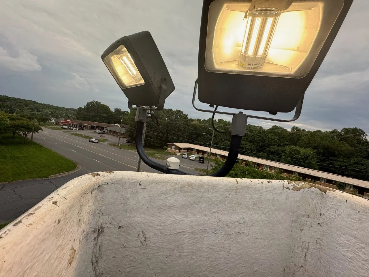 Two flood lights on a pole seen from a bucket truck above a road